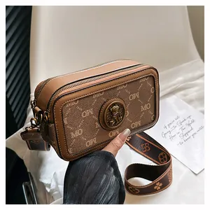 Dettaglio della borsa fotografica retrò con monogramma MO ed emblema in metallo dorato