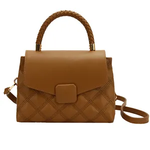 Brown quilted leather handbag with woven handle and gold hardware on white background