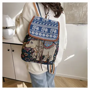 Detail shot of ethnic elephant embroidery and colorful striped strap on a canvas backpack
