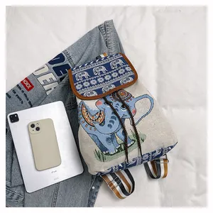 Detailed view of canvas backpack featuring ethnic elephant patterns and striped straps