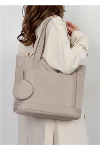 Grande borsa tote in nylon beige con piccolo borsellino indossata da una modella