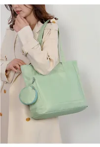 Borsa tote in nylon verde menta con piccolo borsellino rotondo indossata da una modella