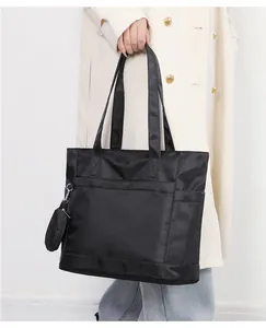 Dettaglio della borsa tote in nylon nero con tasca frontale e mini borsellino rotondo