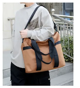 Grand sac fourre-tout en nylon kaki avec larges lanières noires en situation extérieure