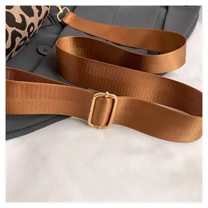 Close-up of adjustable brown strap with gold buckle on leopard print crossbody bag