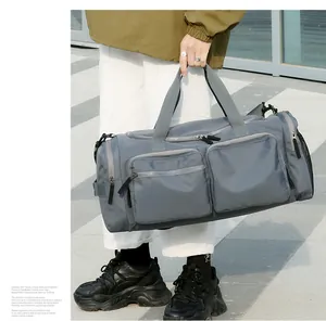 Détail du sac de voyage gris avec tissu en nylon durable et multiples poches zippées