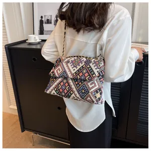 Close-up of woven shoulder bag with colorful geometric patterns and metal chain strap