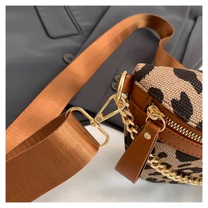 Close-up of leopard print crossbody bag with gold hardware and wide brown strap