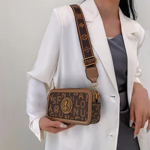 Borsa a tracolla con stampa a lettere e spallina larga indossata su abito bianco