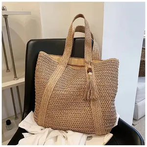 Detail of hand-woven crescent beach tote bag featuring wooden bead tassel and wide handle