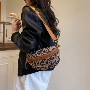 Leopard print crossbody bag with chain detail on model in cozy cafe setting