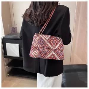 Close-up of ethnic style woven crossbody bag featuring geometric patterns and chain strap