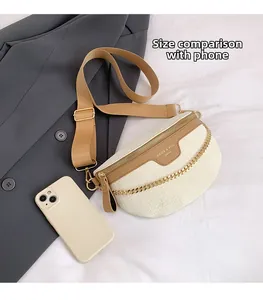 Sac banane à motif crocodile avec chaîne dorée et bandoulière à côté d'un téléphone