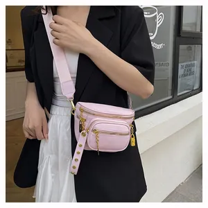 Dettaglio borsa a tracolla rosa con catena dorata, tasche con zip e tracolla regolabile