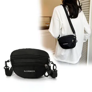 Detailed view of black nylon crossbody bag with multi-zipper layers and adjustable strap