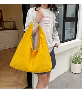 Dettaglio borsa tote in nylon giallo con texture a coulisse laterale e tracolla larga