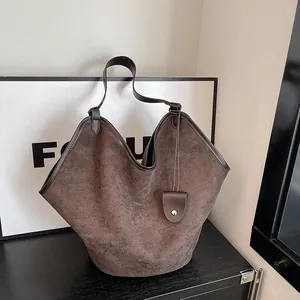 Détail d'un grand sac cabas en daim marron foncé avec bandoulière et fermeture à pression