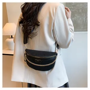 Détail du sac demi-lune noir avec texture tressée et chaîne dorée sur mannequin