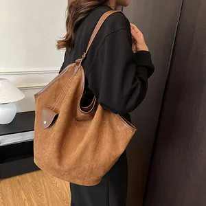Détail d'un grand sac cabas en daim marron avec bordure en cuir et pochette assortie