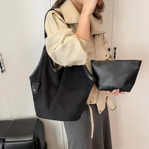 Vue détaillée du sac cabas en daim noir et de la pochette en cuir portés par un mannequin