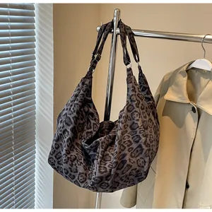 Detail of adjustable silver buckle and leopard print strap on canvas hobo bag