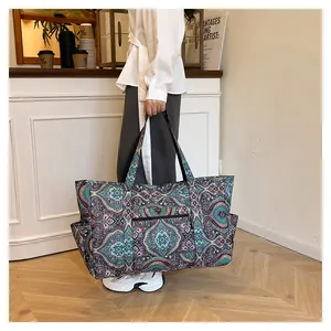 Detalle de bolsa de viaje con estampado paisley y asas negras en una cafetería