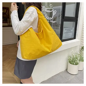 Borsa tote in nylon giallo vibrante con tessuto testurizzato mostrata in un contesto outdoor casual