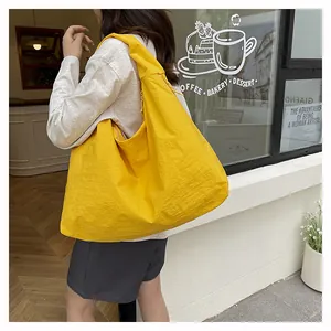 Vista laterale dettagliata di una grande borsa tote in nylon giallo indossata da una modella