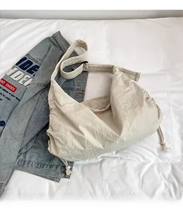 Detail view of large beige nylon dumpling bag with drawstring and wide shoulder strap