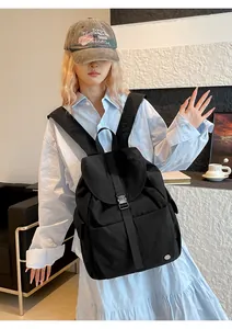Zaino nero in nylon impermeabile con patta e fibbia indossato da una modella