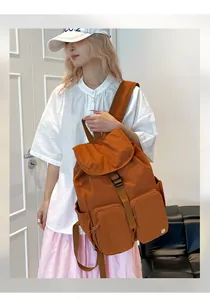 Dettaglio dello zaino in nylon caramello con tasche multiple e chiusura con fibbia