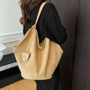 Détail du sac cabas en daim camel porté à l'épaule avec texture et mini pochette