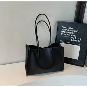 Close-up scene view of black leather tote bag, minimalist style, double handle design.