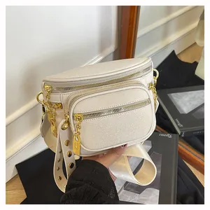 Dettaglio borsa a tracolla in pelle crema con zip dorate e spallina con borchie