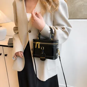Detail der schwarzen glänzenden Handtasche mit goldenem Reißverschluss und Lederriemen