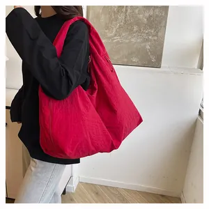 Borsa tote in nylon rosso con trama a pieghe indossata da una modella per l'ufficio