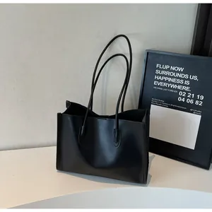 Close-up detail of black soft leather tote bag showing fine texture and double shoulder straps.