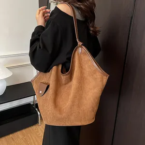 Détail macro du cabas en daim marron avec bordure en cuir et petit accessoire de pochette