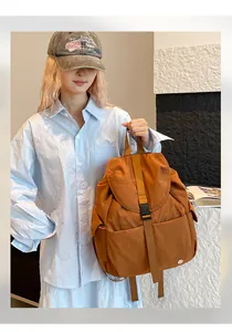 Scatto lifestyle di uno zaino in nylon caramello con fibbia e tasche laterali