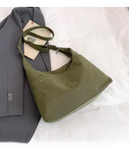 Détail du sac hobo à carreaux vert foncé avec bandoulière réglable sur un blazer