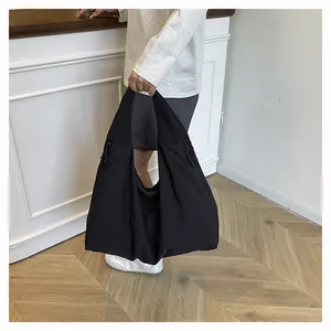 Dettaglio della borsa tote in nylon nero con trama resistente e tasca laterale con zip