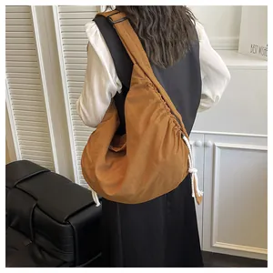 Detail of adjustable metal buckle and wide shoulder strap on caramel nylon crossbody bag