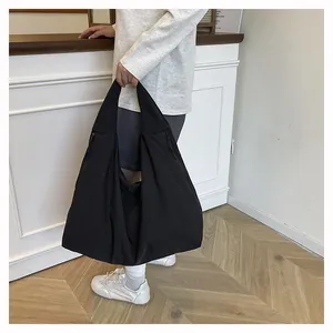 Dettaglio della borsa tote leggera in nylon nero pieghettato con cerniera laterale per ufficio