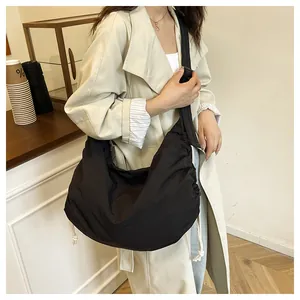 Lifestyle view of a black nylon crossbody bag with side drawstring detail in a cafe