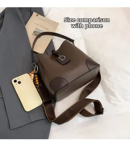 Bolso saco marrón granulado con hebilla en D y móvil para referencia de tamaño