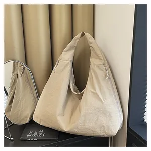 Vista dettagliata della borsa tote in nylon kaki con lacci laterali e chiusura a zip