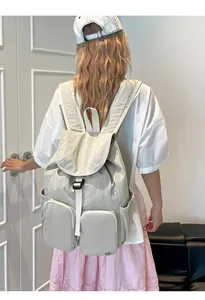 Vista laterale dettagliata di uno zaino in nylon beige con tasche multiple su modella