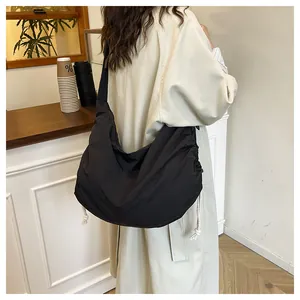 Detail of a large black nylon dumpling bag with white side drawstrings on model