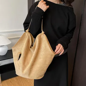 Détail d'un grand sac cabas en daim camel avec bord ondulé porté par un mannequin
