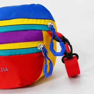 Detail of durable nylon fanny pack showing colorful patchwork and blue plastic zippers